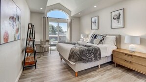 A bedroom with a bed, bedside table, and artwork on the walls. - @ Marbella Lane - Modern 3BR Home w/ Ocean Views (Pacifica)