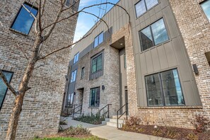 A modern building with a brick facade, large windows, and a staircase leading to an entrance. - Nashville Group Stay • 2 Homes Sleeps 28 (Nashville)