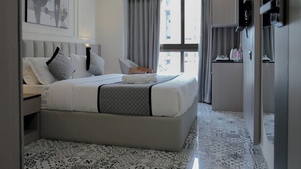 Una habitación de hotel moderna con una cama grande, un ventilador de techo, una ventana con cortinas y un televisor montado en la pared.