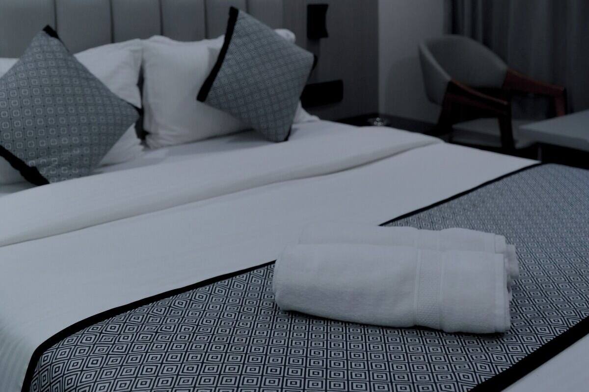 Camera d'albergo moderna con un letto grande, una ventola a soffitto, un quadro appeso e vista all'esterno.
