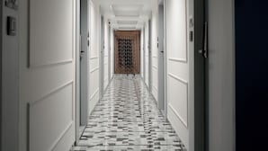 Un pasillo largo y estrecho con paredes blancas y un suelo con estampado de cuadros.
