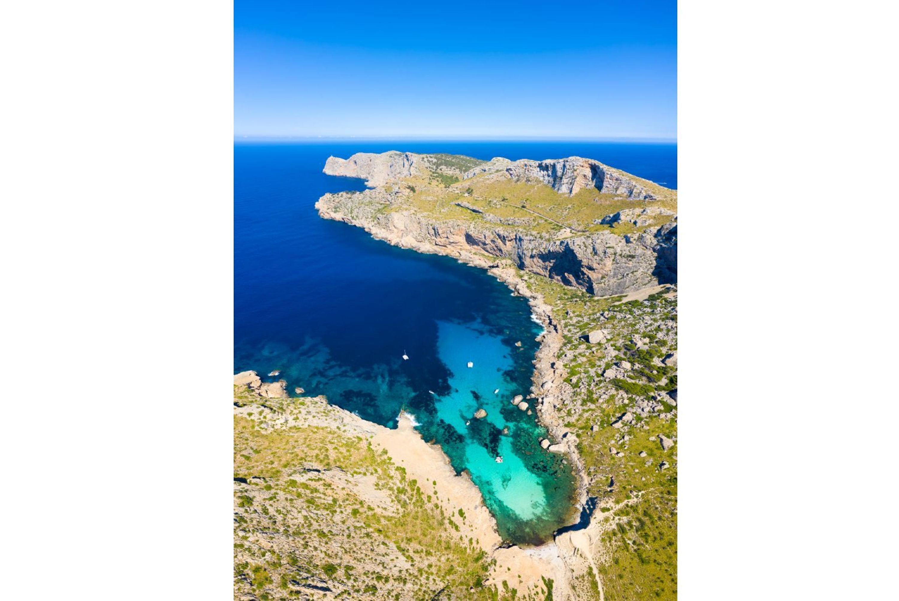 Vista aérea de un paisaje costero con terreno rocoso y aguas azules cristalinas.