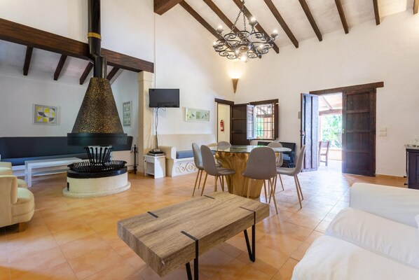 A spacious living area with a wooden table, chairs, a sofa, and a fireplace.