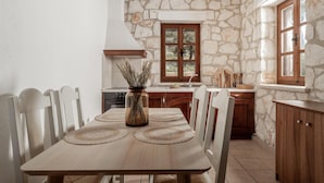 Una cocina rústica con pared de piedra, armarios de madera y una mesa de comedor con sillas.