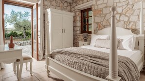 Un dormitorio con pared de piedra, una cama de madera, una mesita de noche y un escritorio con una silla.