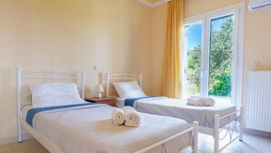 Een hotelkamer met twee bedden, een raam met gordijnen en een radiator.