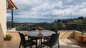 Een ronde tafel met stoelen op een balkon met uitzicht op een schilderachtig landschap.