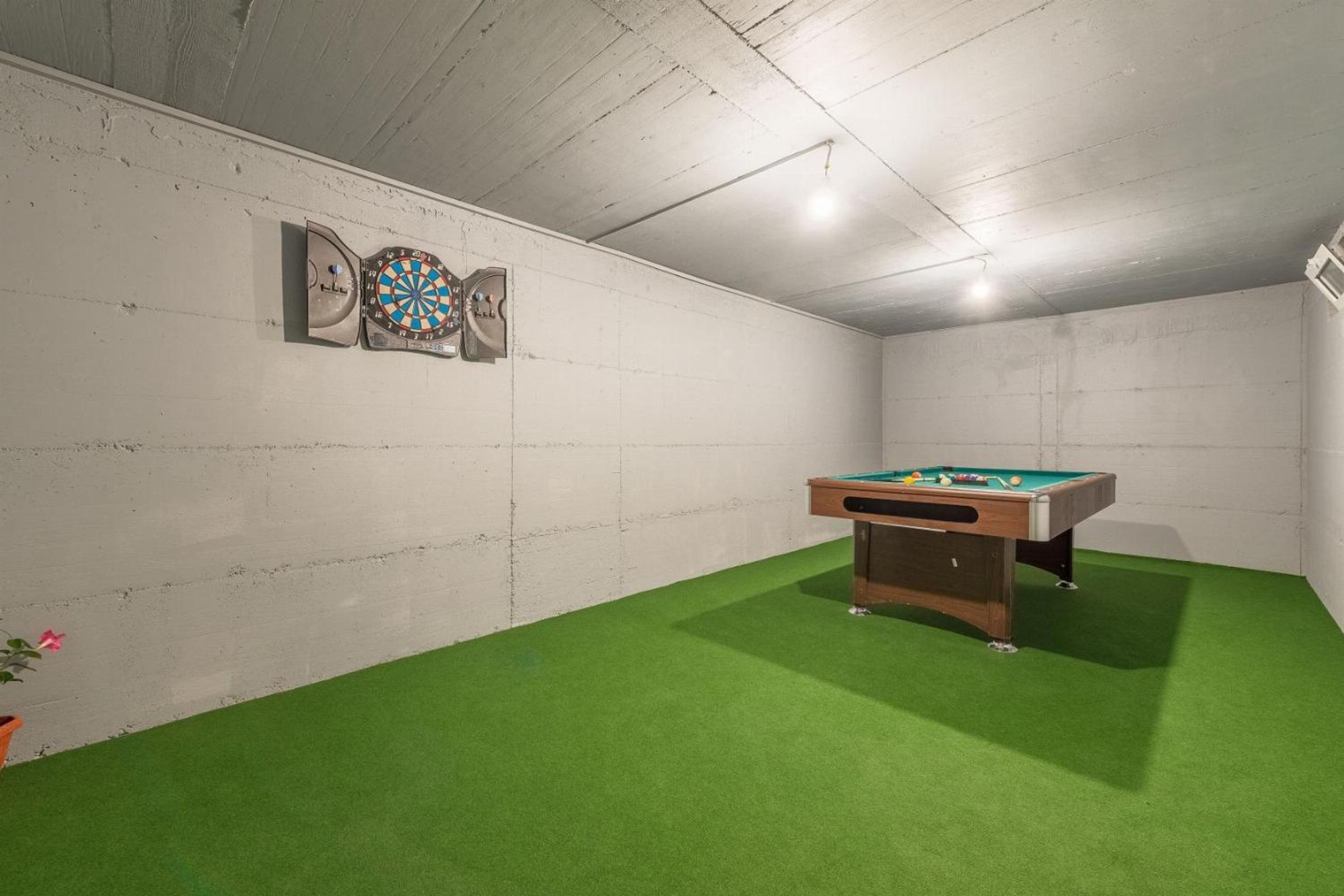 Een kamer met een pooltafel, kunstgras in het groen en dartborden aan de muur.