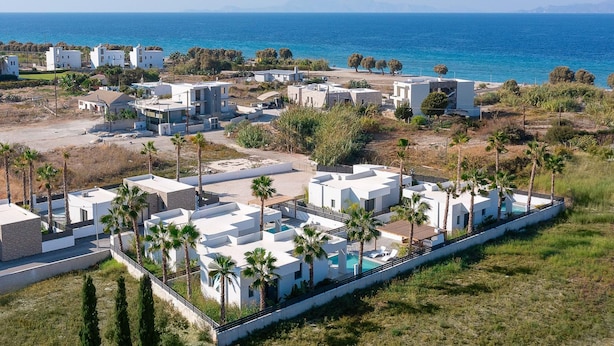 A coastal resort with modern white buildings, a swimming pool, and palm trees. - Salty Sun 4 in Kremasti (Rhodes)
