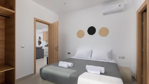 A bedroom with a bed, a wardrobe, a mirror, and a wall-mounted air conditioner. - Salty Sun 4 in Kremasti (Rhodes)