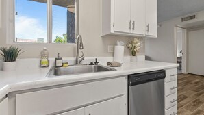 A modern kitchen with a dishwasher, a sink, and white cabinetry. - Pool -Gym- Great for Mid/Long Stays (Mesa)