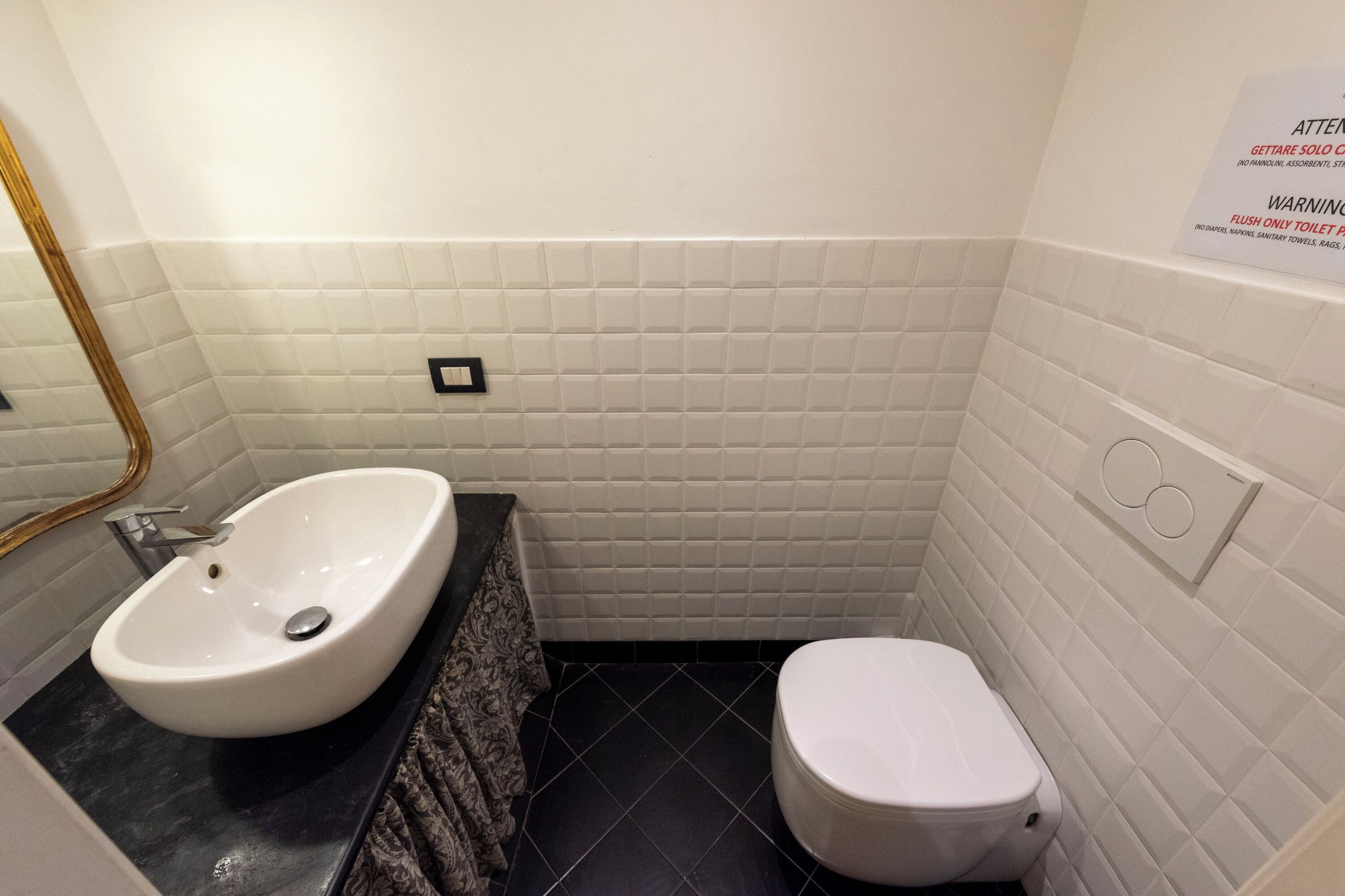 Un baño con un lavamanos blanco, un inodoro y un espejo.
