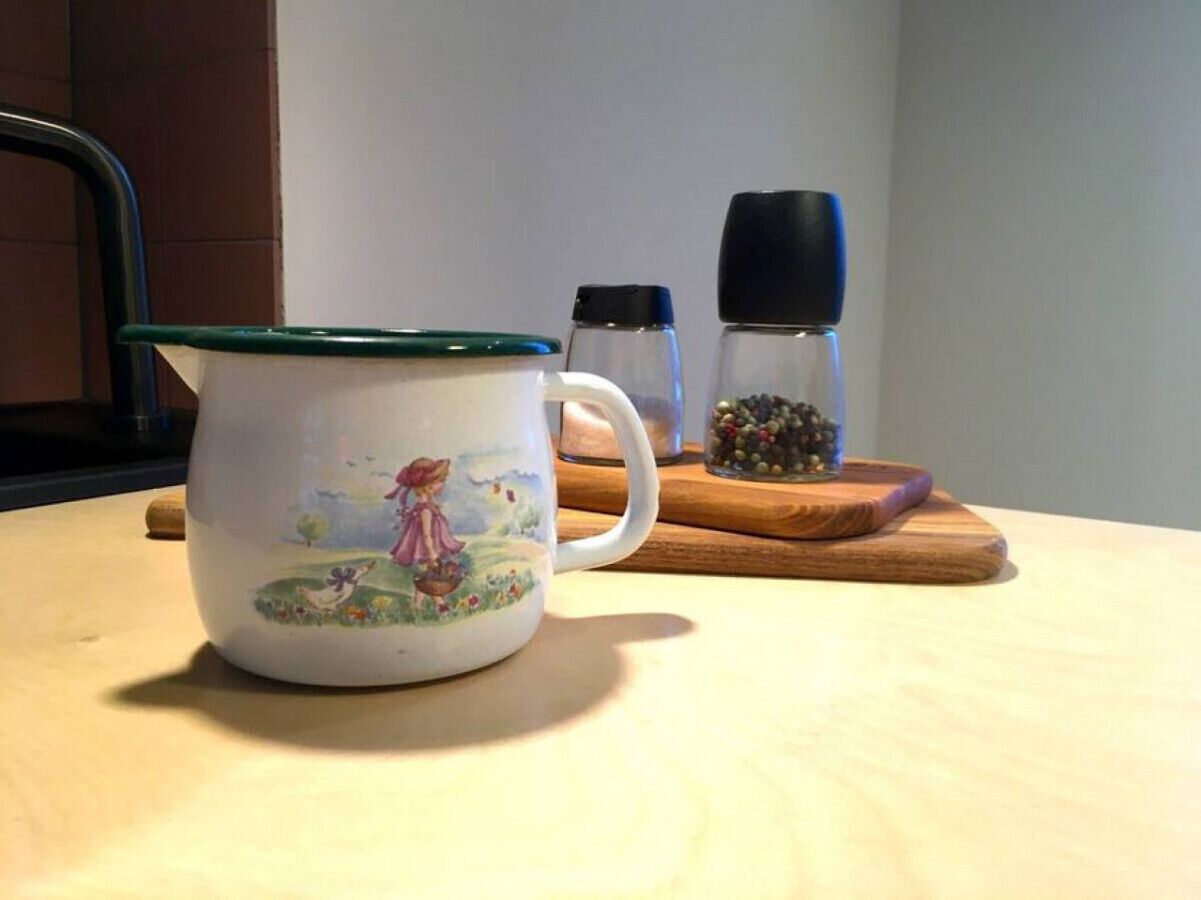 Una taza de cerámica con tapa verde sobre una mesa de madera.