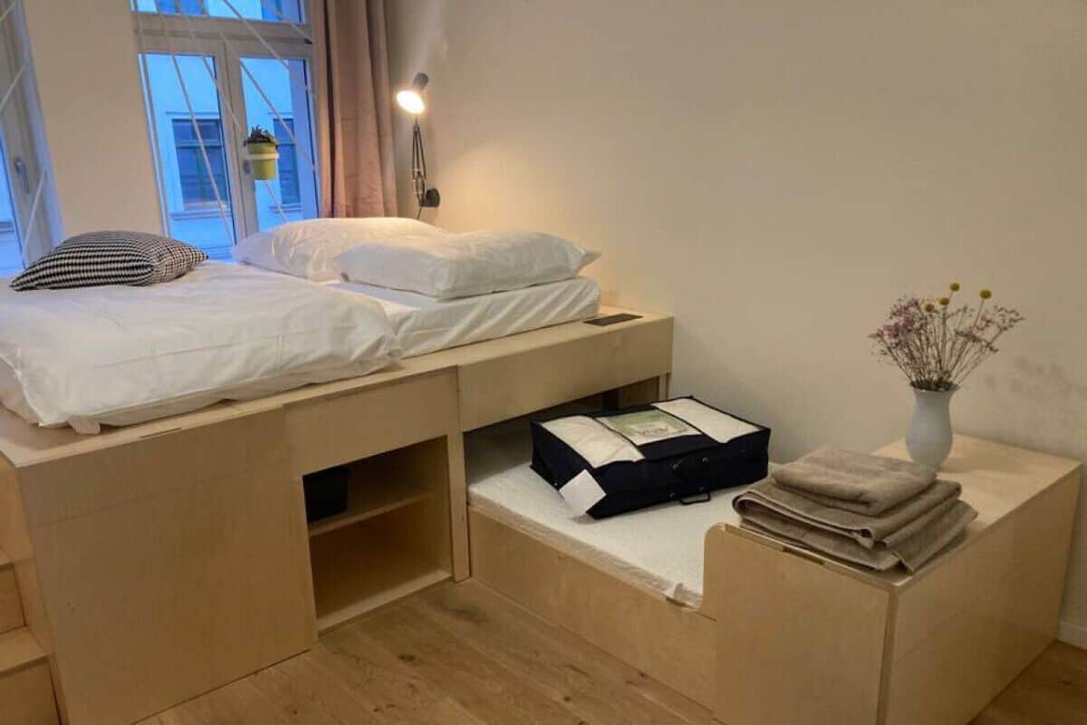 Un dormitorio compacto con cama, mesita de noche y un pequeño escritorio.