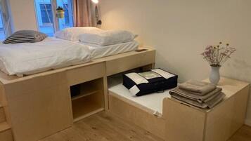 A compact bedroom with a bed, bedside table, and a small desk area.