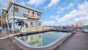 Zona de piscina con vista despejada a la pileta, un edificio con balcón y un paisaje urbano al fondo.
