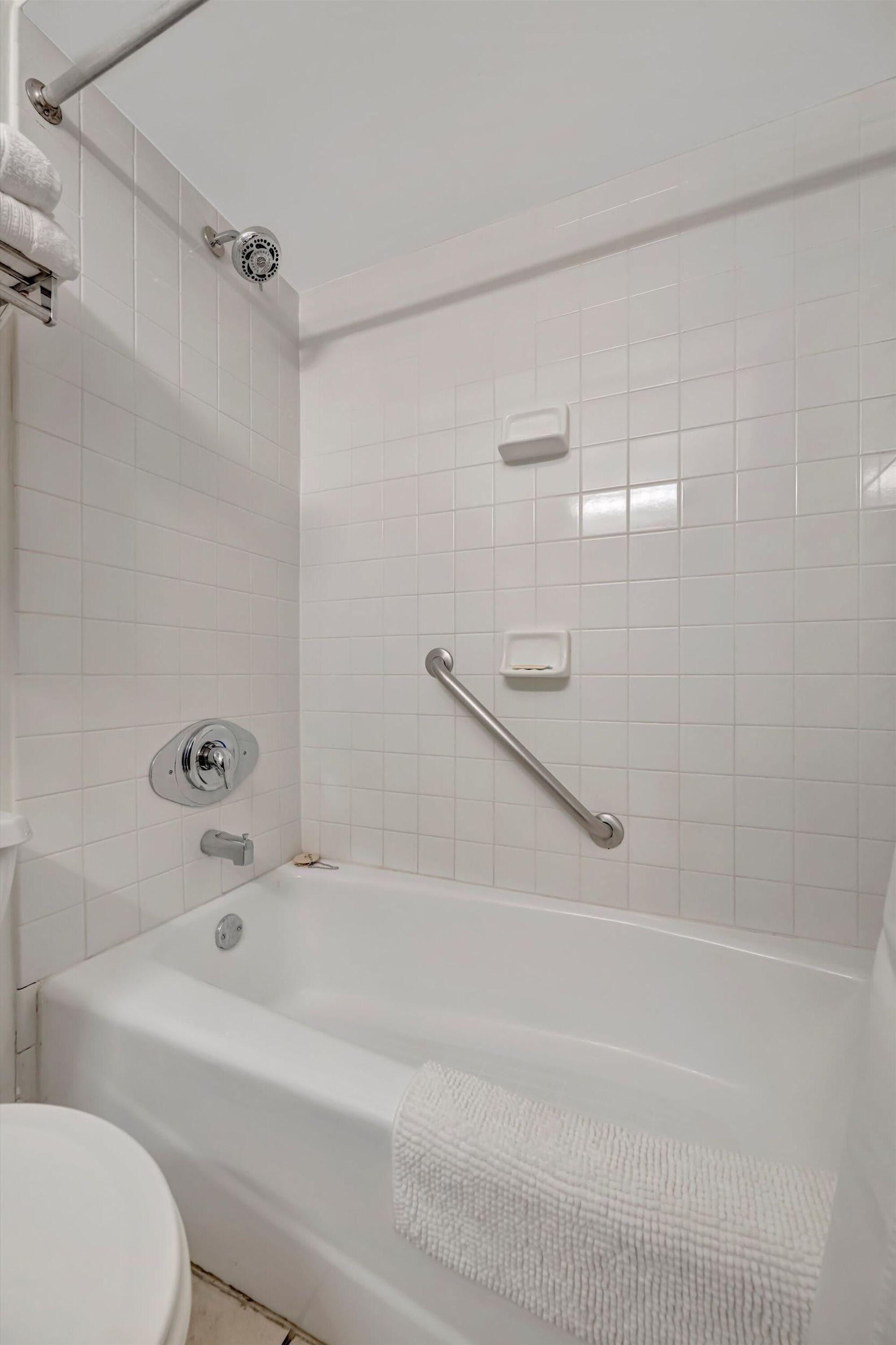 A bathroom with a white bathtub, a toilet, and a shower area.