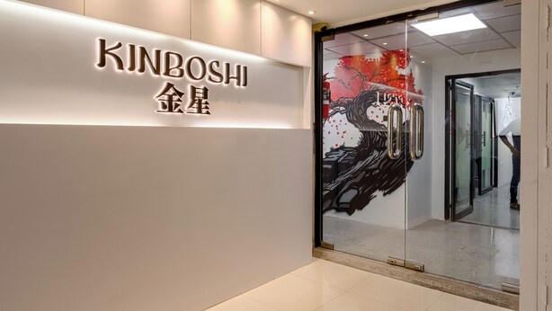 Een modern interieur met een bord waarop 'KINBOSHI 金星' staat en een glazen deur met een abstract ontwerp in rood en zwart.