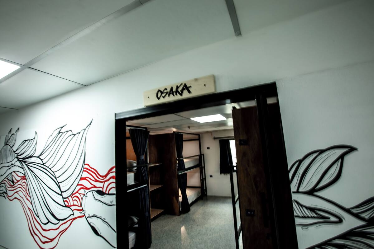 Huoneessa on kerrossängyt, seinämaalaus ja kyltti, jossa lukee ”OSAKA”.