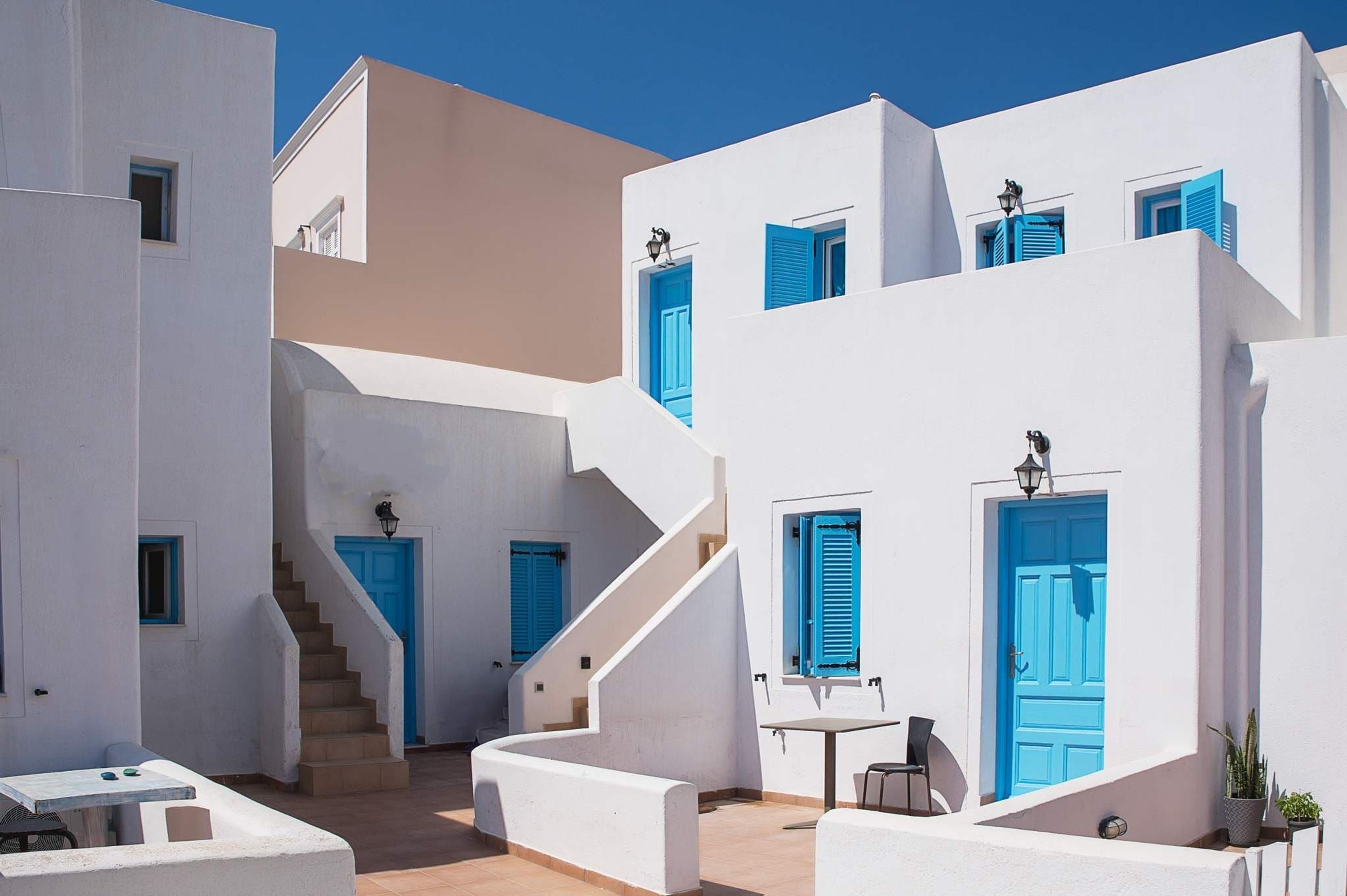 A white building with blue shutters and a staircase leading to an upper level.