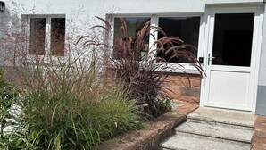 A house with a white exterior, a front door, and a small porch area with steps leading up to the door. - Vacation apartment in a quiet location, directly on the premium hiking trails (Dahn)