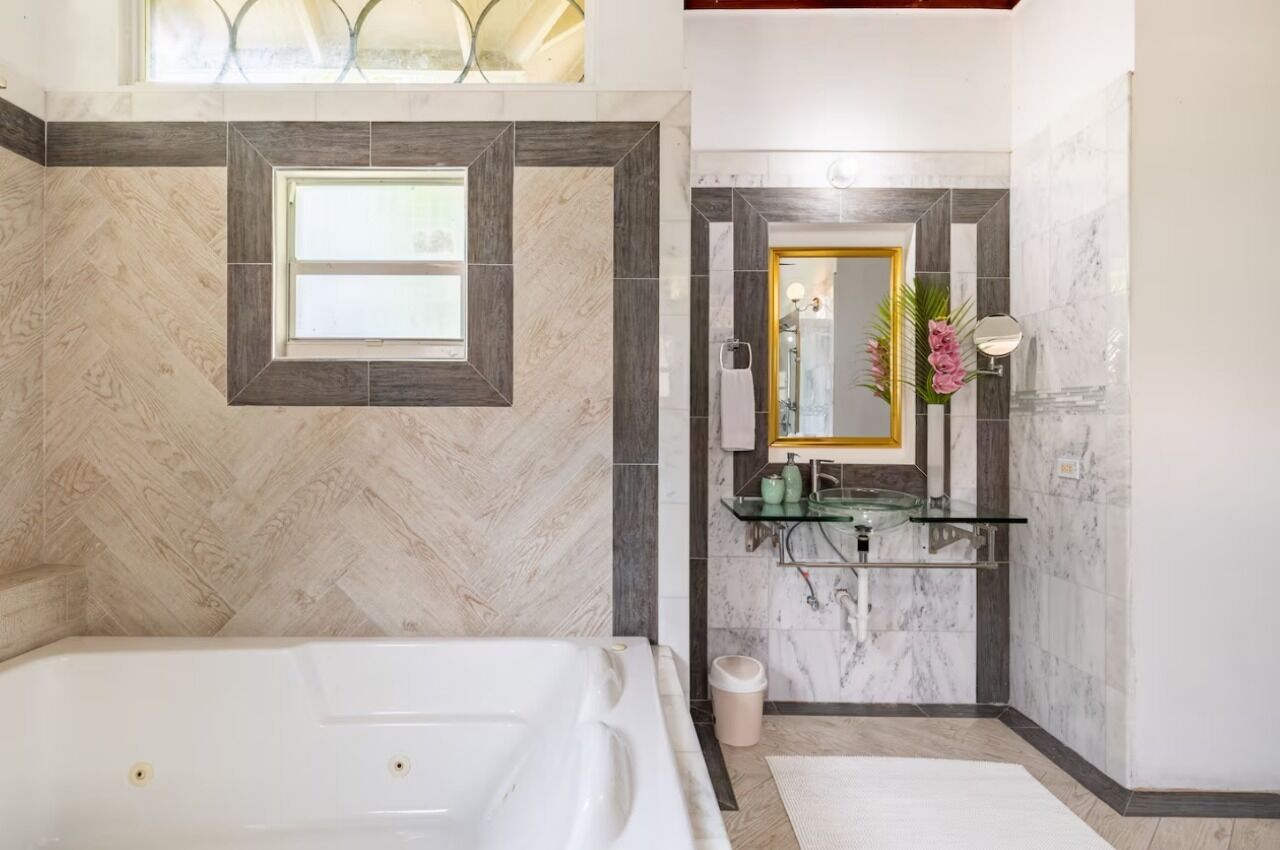 Une salle de bain moderne avec une grande baignoire, une douche en verre et un mur recouvert de carreaux de marbre.