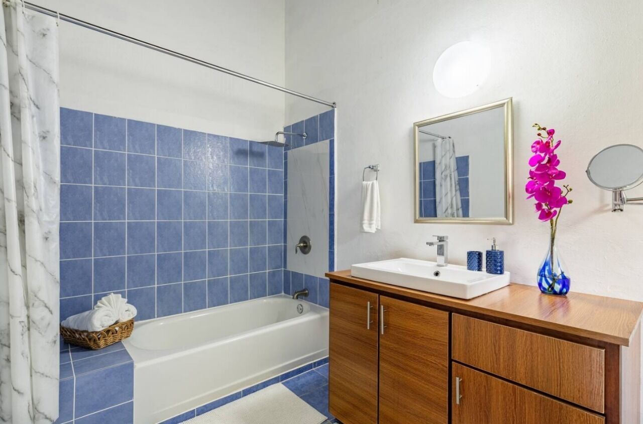 A bathroom with a bathtub, a sink, and a mirror.