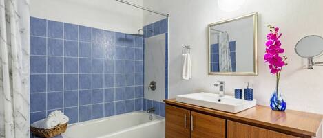 A bathroom with a bathtub, a sink, and a mirror.