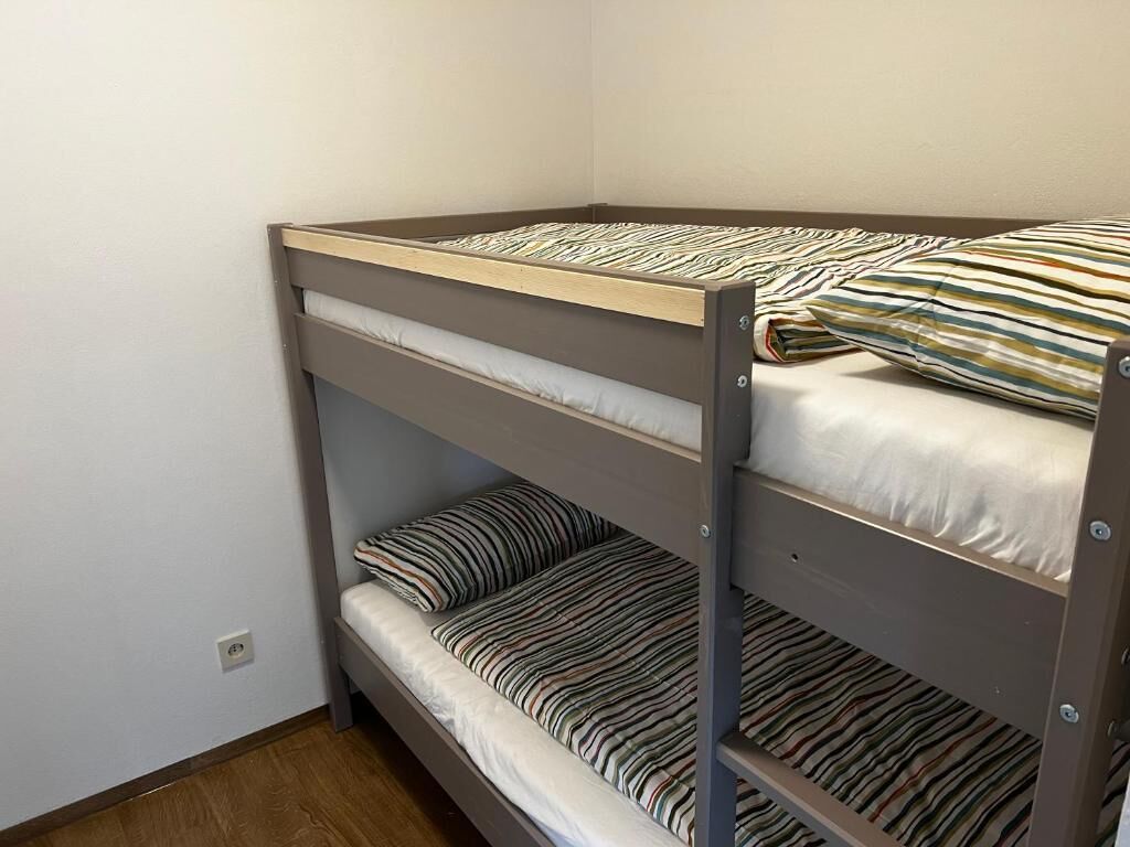 A bunk bed with striped bedding in a room with plain walls and wooden flooring.