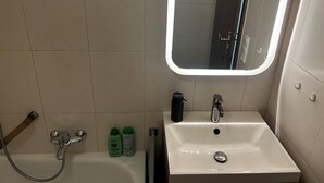 A bathroom with a white sink, a mirror, and two bottles of shampoo. - Vacation apartment in Prien am Chiemsee (Prien am Chiemsee)