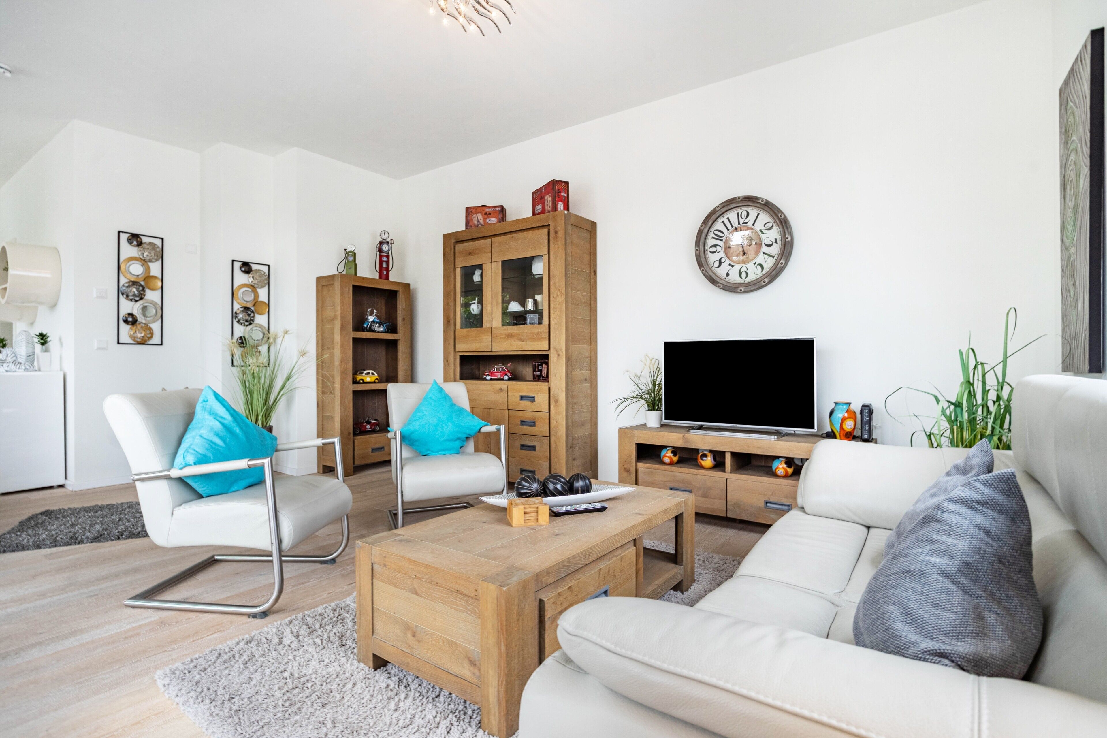 Un salon moderne comprenant un canapé, une table basse, un téléviseur, des meubles en bois et des objets décoratifs.