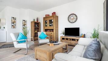 Un salon moderne comprenant un canapé, une table basse, un téléviseur, des meubles en bois et des objets décoratifs.
