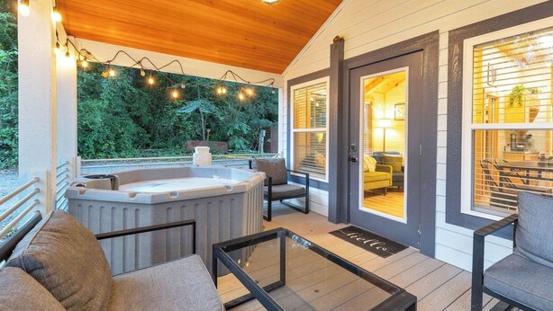 Un espacio al aire libre techado con un jacuzzi, asientos e iluminación colgante.