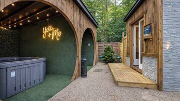 Un bâtiment en bois, orné d’une enseigne au néon, doté d’un jacuzzi et d’une terrasse en bois.