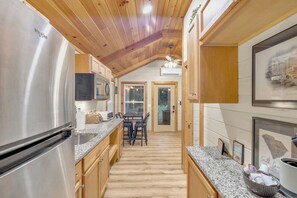 A kitchen with wooden cabinets, a stainless steel refrigerator, granite countertops, and a dining area with a table and chairs.