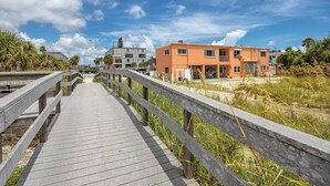 A wooden boardwalk leading to a building with a flat roof and multiple windows. - Beachside at Birdsong #17 Pool 5 Steps to the Sand (Treasure Island)