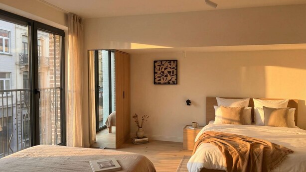 A hotel room with two beds, a large window, a door leading to a balcony, and a small table with a cup. - TurnKey | Henry's Tower Apartment II-3 (Hlavní město Praha)