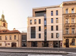 A multi-story building with a modern facade, a visible entrance, and a street corner setting.