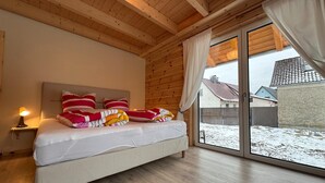 Ein Schlafzimmer mit einem Bett, Holzboden und Blick auf einen verschneiten Garten.