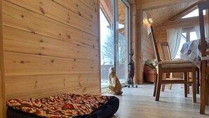 Ein gemütliches Zimmer mit Holzwänden, einem gemusterten Teppich, einem Stuhl und einer kleinen Statue.
