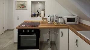 Een kleine keuken met een inbouwoven, een magnetron en een broodrooster.