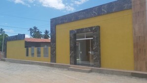 A modern building with a yellow facade and marble accents. - Pousada Estrela Mar  (Jandaira)