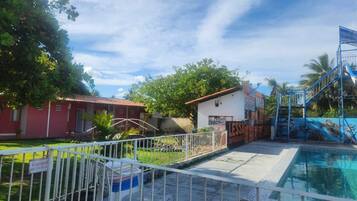 A swimming pool area with a fenced deck, a small building, and a mural.