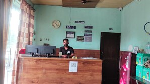 Mostrador de recepción de hotel con un reloj, carteles y un extintor.