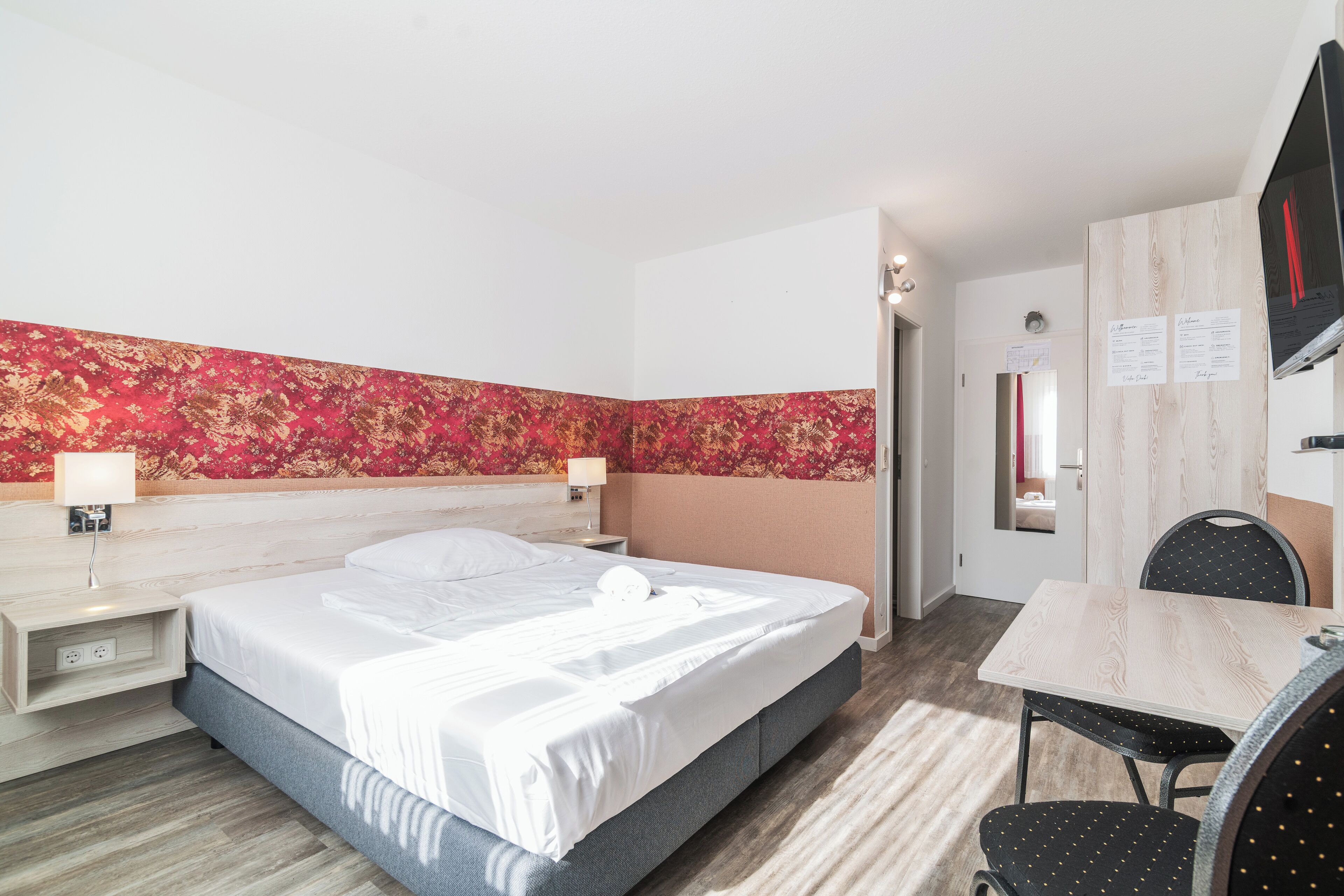 Una habitación de hotel con cama, mesitas de noche, escritorio y una silla.