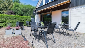 Een terras met tafels en stoelen, een potplant en een gebouw met een bord waarop 