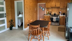 Una cocina compacta con armarios de madera, una mesa de comedor con sillas, un refrigerador y una estufa.
