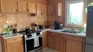 Una cocina moderna con armarios de madera, electrodomésticos de acero inoxidable y un ventanal que proporciona luz natural.