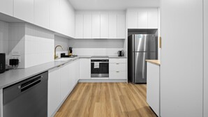 A modern kitchen with white cabinets, a stainless steel refrigerator, and a dishwasher. - Beachside Bliss on Palm Avenue (Surfers Paradise)