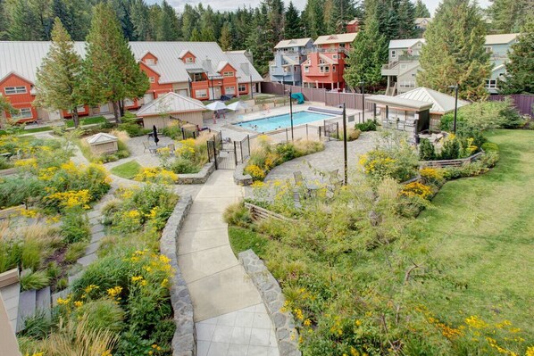 A residential area with a swimming pool, stone pathways, and houses with red and blue exteriors.